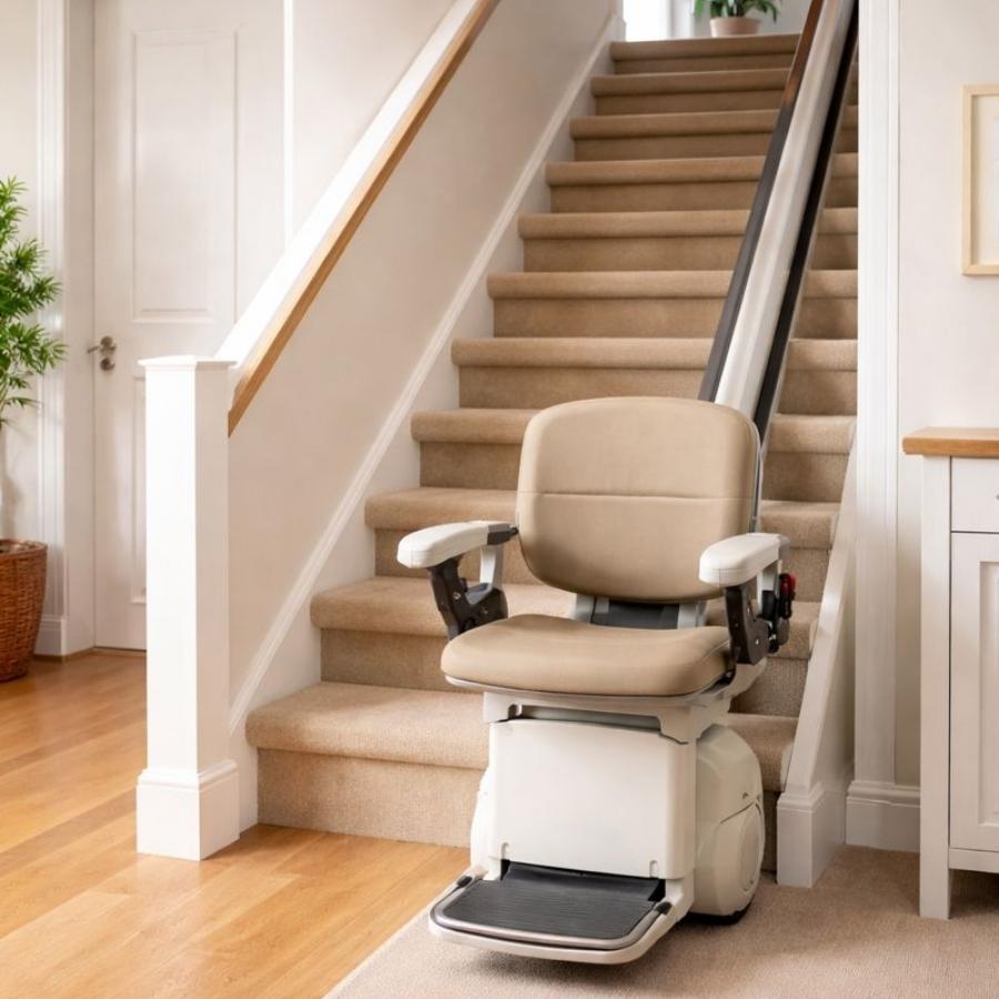 Tan residential stair lift with a padded swivel seat and folding armrests installed on a straight carpeted staircase in a Tybee Island, GA home.
