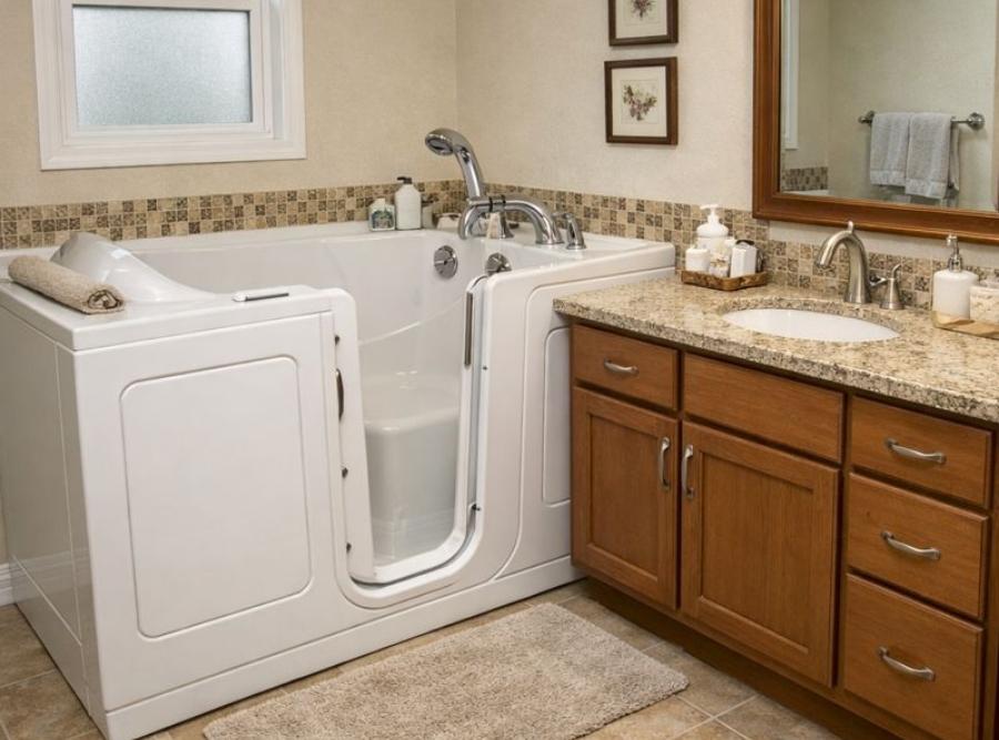 
Luxurious white walk-in soaking tub with an outward-opening door, integrated seat, and handheld showerhead installed in a Darien, GA bathroom.