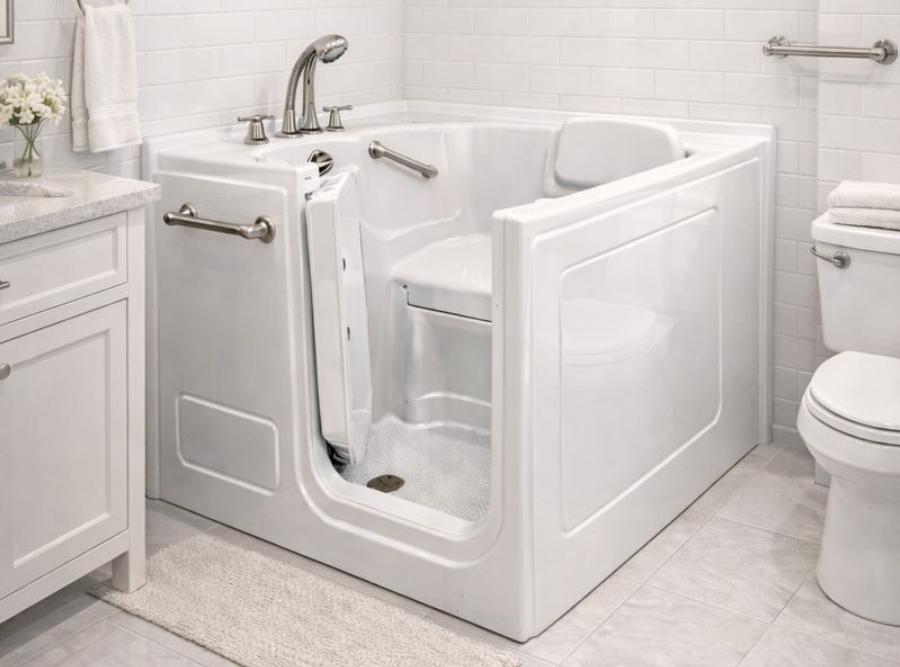 White walk-in safety bathtub with an inward-opening door, built-in seat, and chrome grab bars in a Sea Island, GA bathroom.
